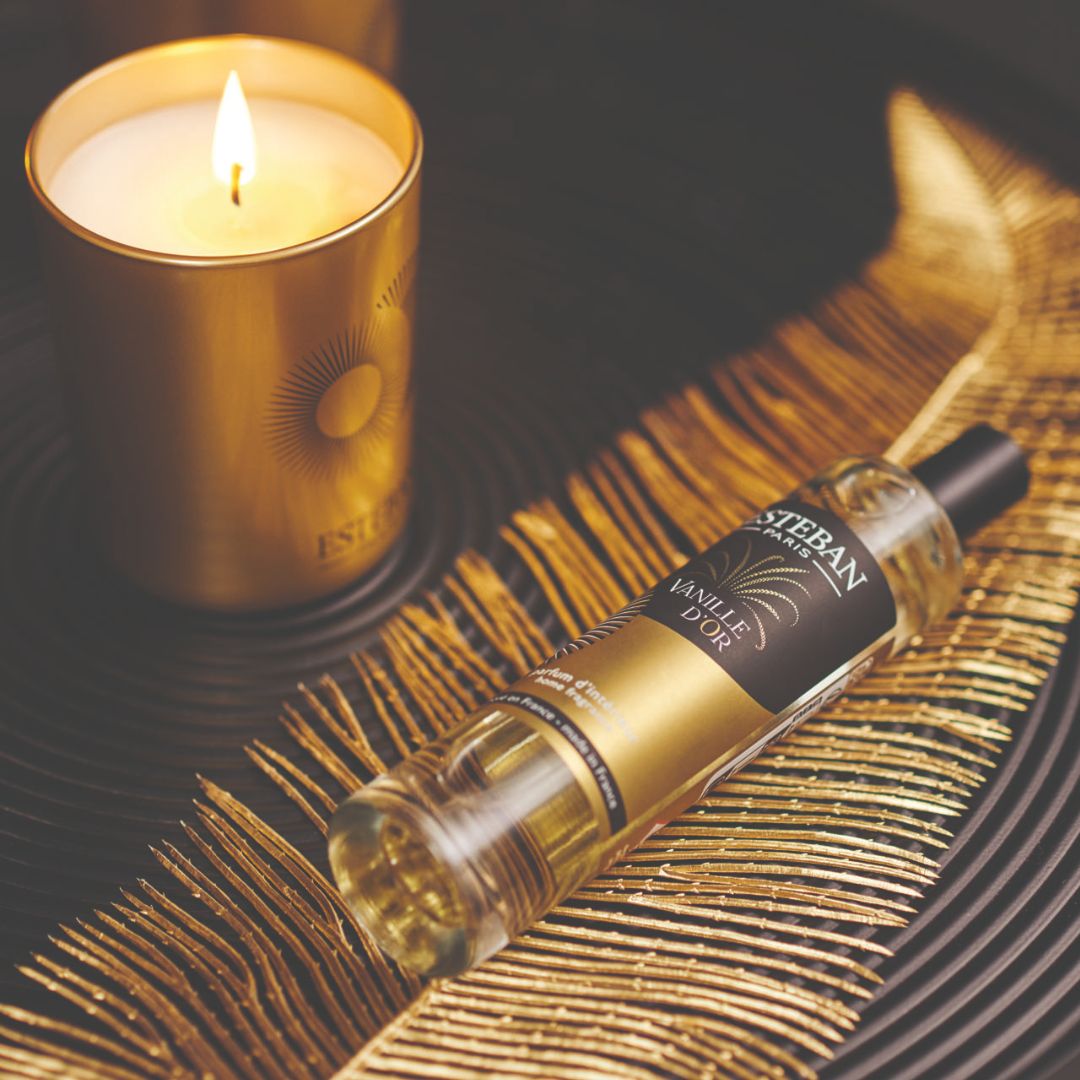 Parfum d’intérieur Esteban Paris Vanille d’Or en spray, flacon vaporisateur présenté sur un plateau décoratif doré aux côtés d’une bougie parfumée allumée dans une ambiance chaleureuse et raffinée
